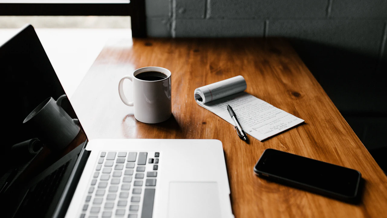 Laptop, taza y teléfono sobre un escritorio